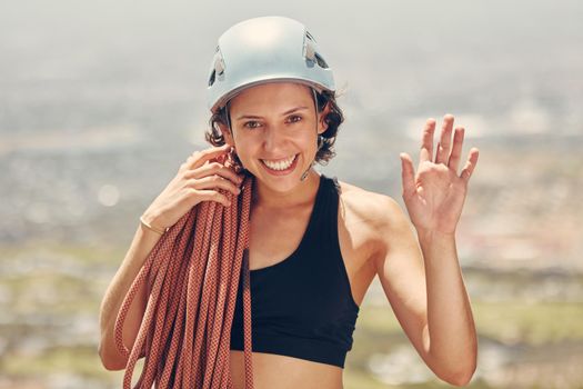 Rock climbing, rope and woman portrait happy to challenge her fitness and hiking outdoors in nature adventure. Helmet, smile and mountain climber girl waving and ready for exercise and sports workout