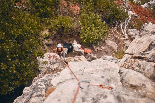 Climbing, abseiling and adventure with a woman climber hiking on a mountain outside in nature, the woods or the forest. Sports, health and fitness with a female holding a rope and scaling a rock