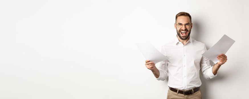 Angry boss disappointed with documents, shouting mad and aggressive, standing over white background