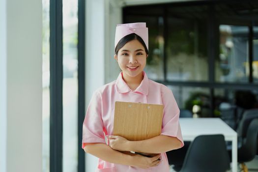Portrait of a young nurse in a pink dress smiling happily