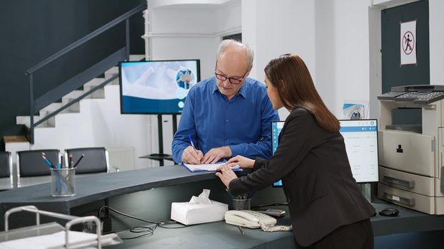 Senior man filling in checkup report papers before appointment