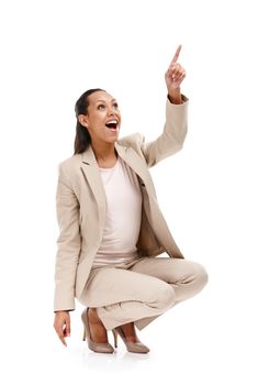 Set the bar high. Full length shot of an attractive young woman in a suit crouching down and pointing upwards isolated on white.