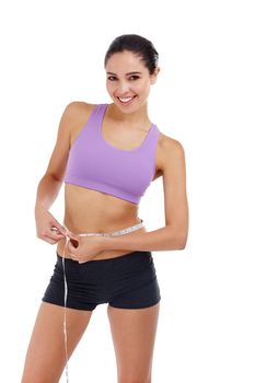 Reaching her goal weight. Three quarter length shot of an attractive young woman in gym clothes measuring her waist.