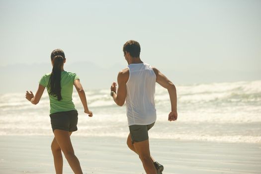 Its funny how things work out sometimes. Rearview shot of a couple jogging along the beach.