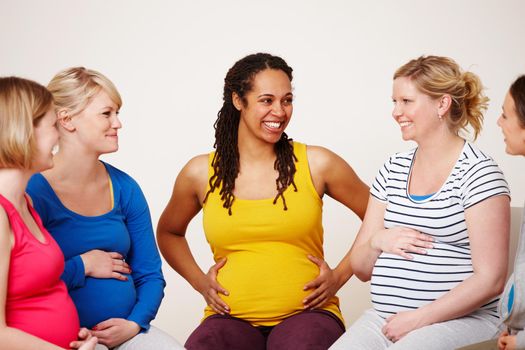 Supporting each other throughout their pregnancies. A multi-ethnic group of pregnant women smiling while sitting together in a circle.