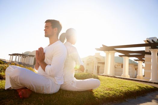 Blissful meditation in the sun. Full length shot of a young couple doing yoga outdoors.