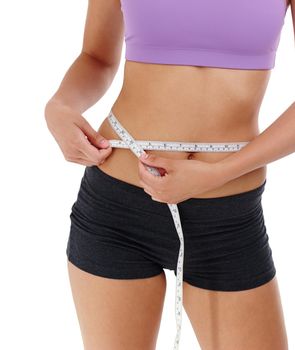 Shedding pounds with good exercise. an unrecognizable woman in gym clothes measuring her waist.