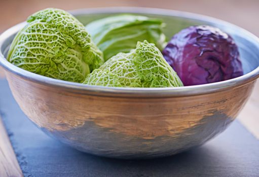 Bowl of delicious produce. a purple and green cabbage in a bowl.