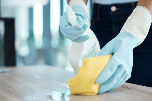 Cleaning, spray bottle and hygiene with woman with gloves for housekeeping, service or disinfectant on table surface. Housekeeper, maid or housewife and cleaner, sanitary and wash at home