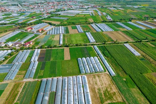 Panoramic view of large greenhouses and fields and houses.