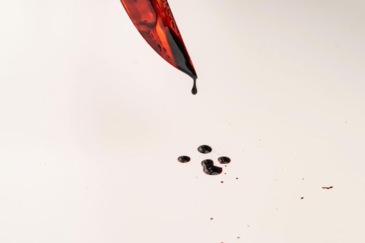 Close-up of a sharp knife covered in blood on a white background.
