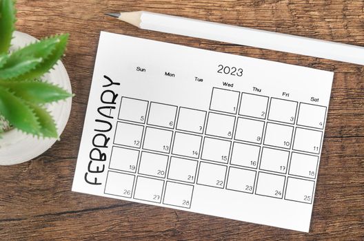 The February 2023 Monthly calendar for 2023 year with pencil on wooden table.