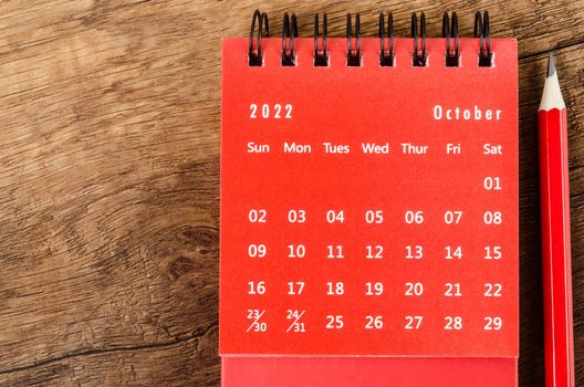 The Red October 2022 Monthly desk calendar for 2022 year with red pencil on wooden background.