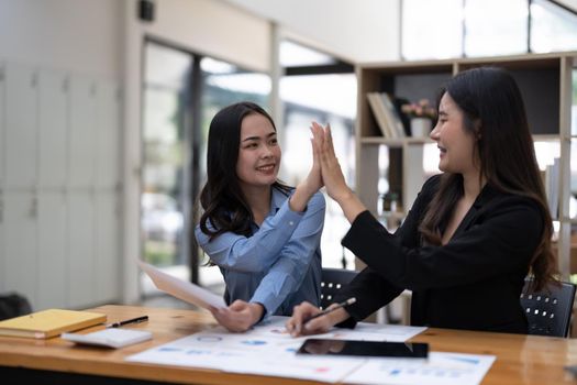 Two people hi five together for thier successful business project in meeting room. Two of business people looking at each other