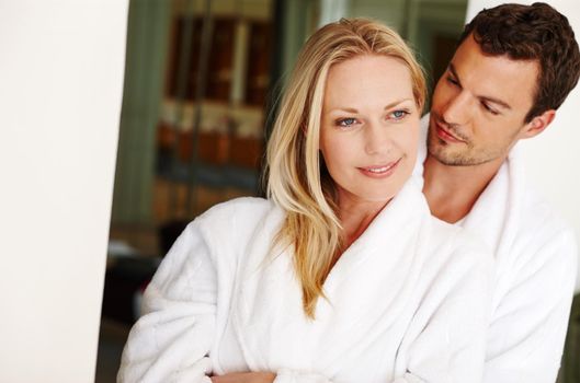 Secure in his love. A loving young couple in bathrobes relaxing at home.