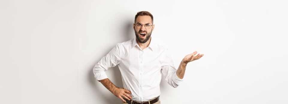 Frustrated office worker complaining, gesturing and looking disappointed, standing over white background