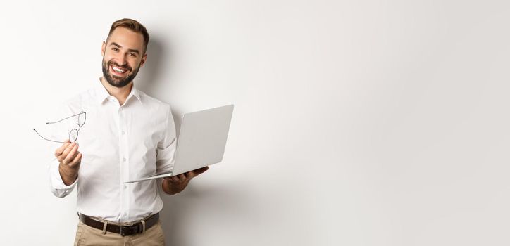 Satisfied businessman praising good job while checking laptop, standing over white background