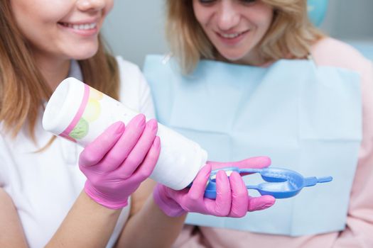 Dentist filling dental mold with dental gel for her mature female patient