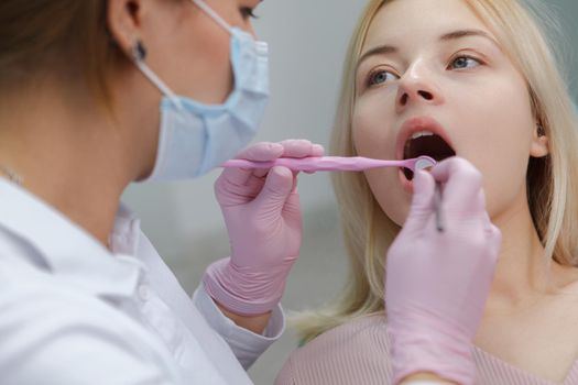 Cropped close up of a young woman having dental examination by professional dentist