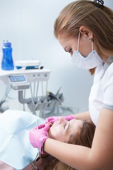Vertical cropped shot of a female dentist working at her clinic, examining teeth of a woman