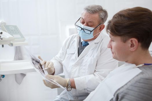 Male patient and his dentist looking at jaw x-ray scan on dental appointment