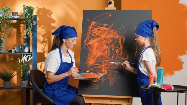 Adult and young kid painting masterpiece on canvas