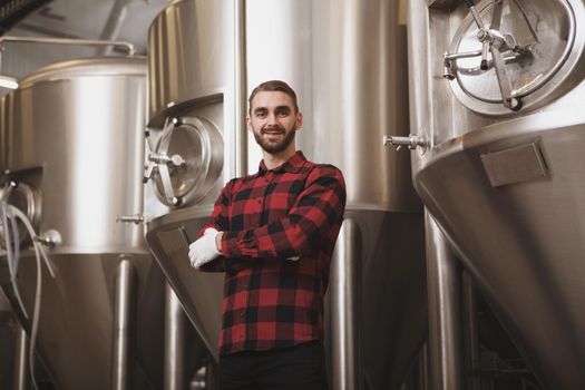 Handsome brewer examining freshly brewed beer at his beer factory