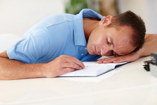 Too much work and no play. an overworked businessman asleep at a desk.