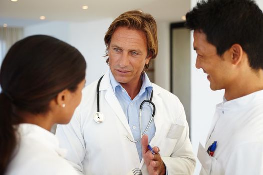 Consulting his medical colleagues. three medical professionals having a conversation at work.