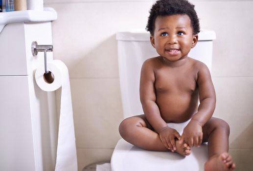 Im ready for my first potty training lesson. an adorable baby boy sitting on the toilet in the bathroom.