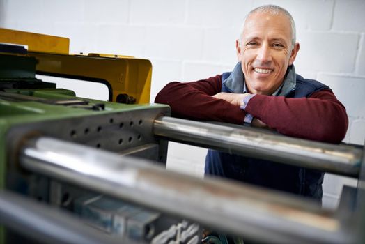 Everything is in perfect working order. Portrait of a mature man standing next to machinery in a factory.