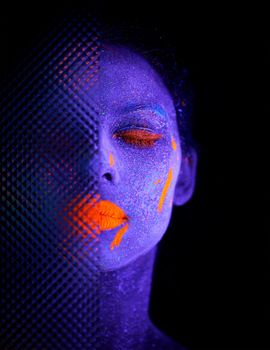 Let your imagination come to life. a young woman posing with neon paint on her face.