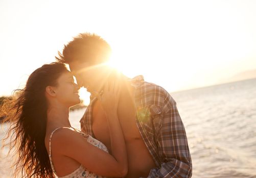 Kisses at sunset. a young couple enjoying a beach getaway.