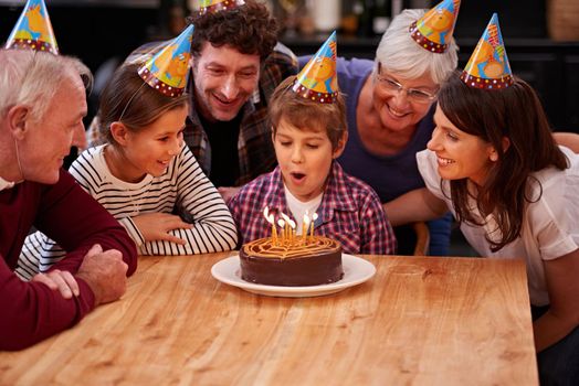 I can blow them out at once. a happy young boy celebrating his birthday with his family.
