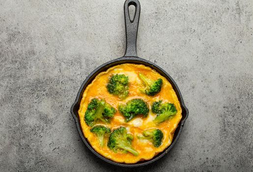 Healthy omelette with broccoli in cast iron pan top view