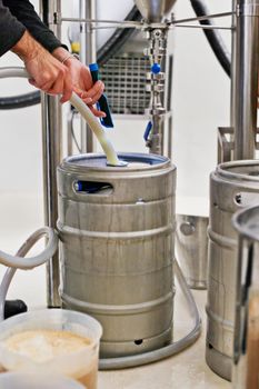 Pouring a perfect brew. a man filling kegs at a brewery.
