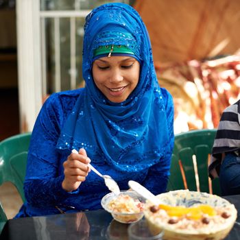 Glad I saved room for dessert. a young muslim woman enjoying a bowl of dessert.