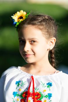 A little Ukrainian and Belarusian girl in an embroidered shirt on a summer background.