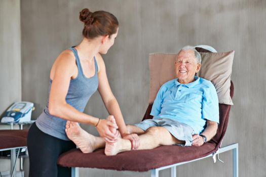 Helping her patients stay strong and healthy. a a physical therapist working with a senior man.