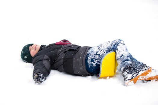 Child in winter. The boy fell on the sled and lies in the snow.