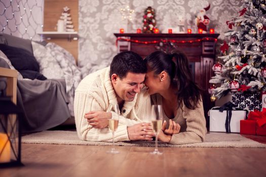 Young wife whispering something on her husband ear celebrating christmas