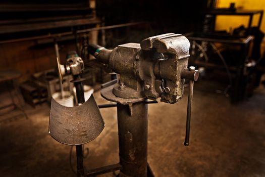 The craft of a bygone era. A free-standing vice in the middle of an iron workers workshop.