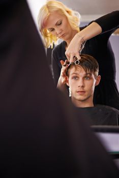 Making sure his hair looks sharp. A young man having his hair styled by a hairdresser.