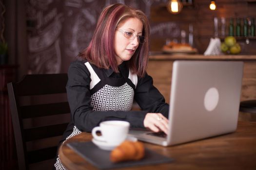 Business person typing on a notebook while serving a coffee