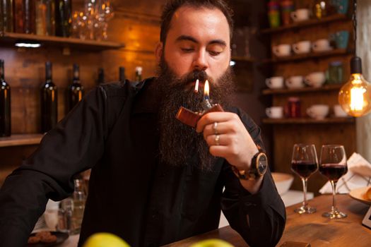 Bearded handsome young bartender lighting his cigarette.