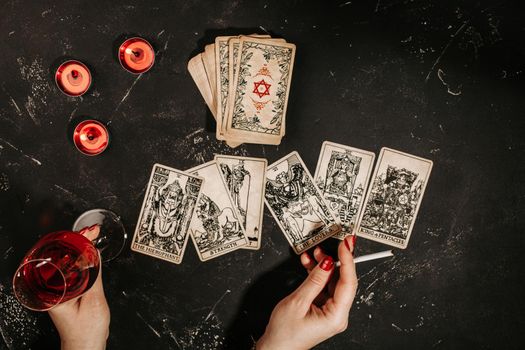 Tarot cards and female hands of fortune teller on black magic table