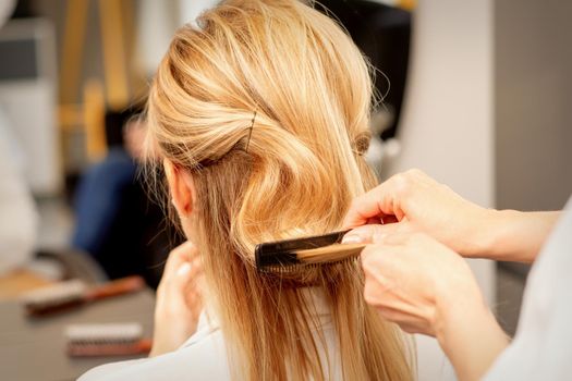 A hairdresser is combing female hairstyling in a hairdressing beauty salon.