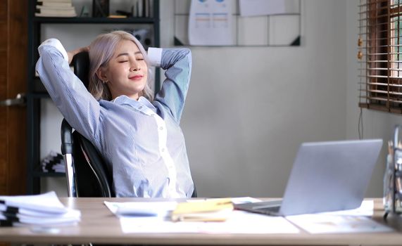 Business asian woman relaxing with hands behind her head and sitting on an office chair