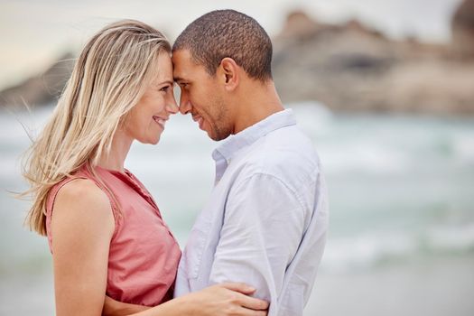 Interracial couple, beach and love bond with forehead together in trust, security or safety. Smile, happy or latino man and woman in hug by ocean or sea water in nature environment for honeymoon date