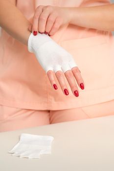 Cosmetologist in workwear wearing white bamboo fingerless gloves on her hands.